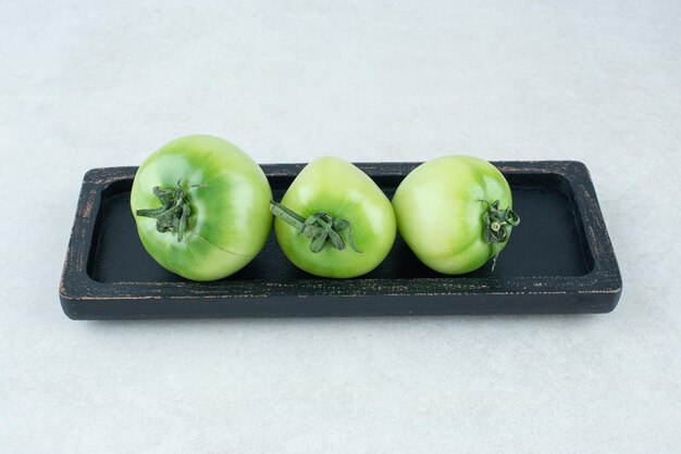 Tomates verdes em conserva na placa preta.