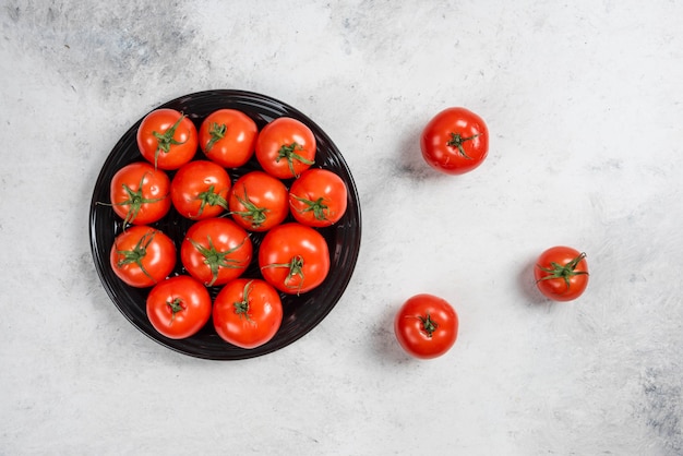 Tomates vermelhos frescos em uma placa preta.