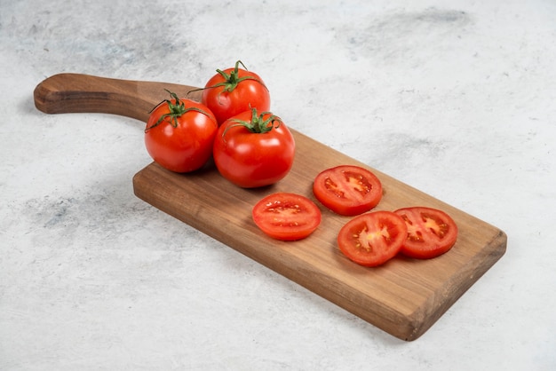 Foto grátis tomates vermelhos frescos em uma tábua de madeira