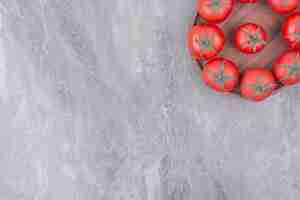 Foto grátis tomates vermelhos isolados em um prato de madeira