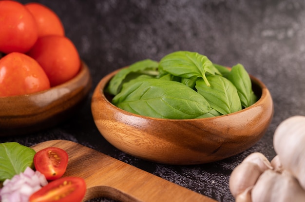 Tomilho e tomate em um copo de madeira com alho em uma tábua de madeira.