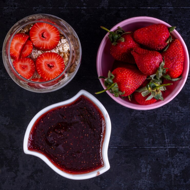 Foto grátis top view granola com frutas e nozes em um copo com morangos em uma tigela rosa e geleia