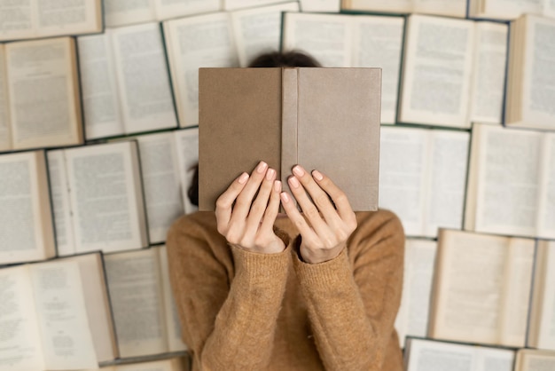 Top view uma mulher em um suéter macio aconchegante deita-se em livros abertos