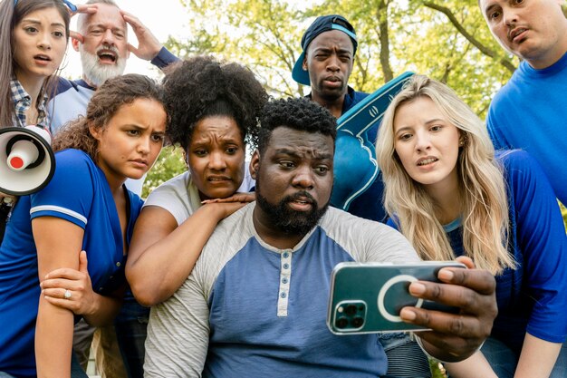 Torcedores de beisebol assistindo seu time perder o jogo em um telefone