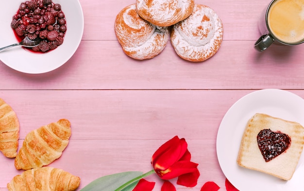 Torrada com geléia em forma de coração com tulipa, frutas e pãezinhos