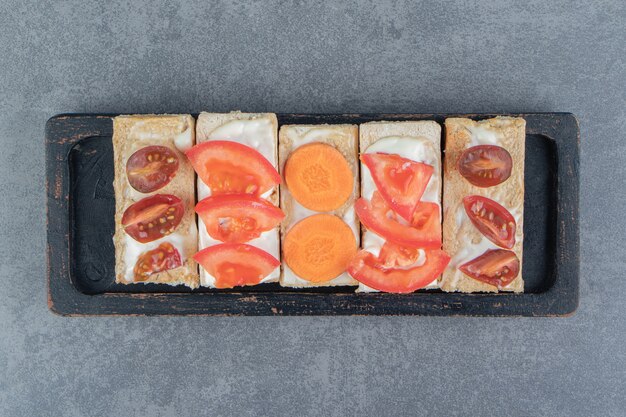 Torradas crocantes com tomate na placa de madeira.