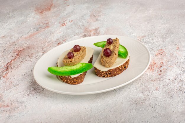 Foto grátis torradas de pão com patê e fatias de pepino em um prato na mesa branca