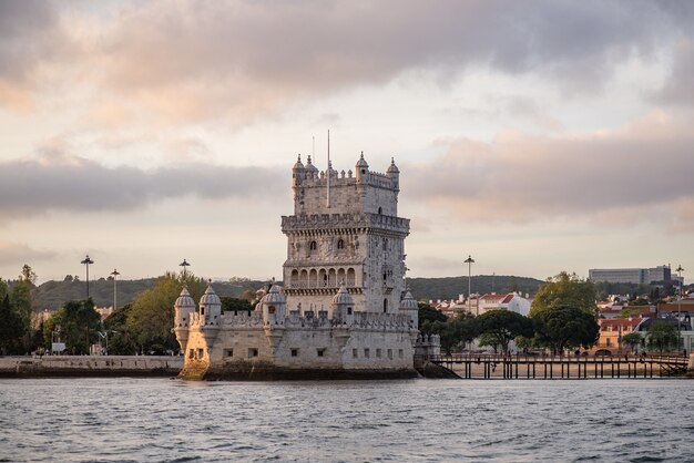 Torre de Belém rodeada pelo mar e edifícios sob um céu nublado em Portugal