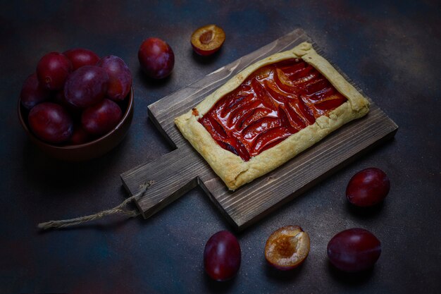 Torta de galette de ameixa fresca com ameixas cruas no escuro