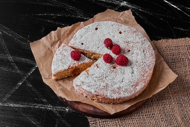 Torta de limão com frutas na travessa de madeira.