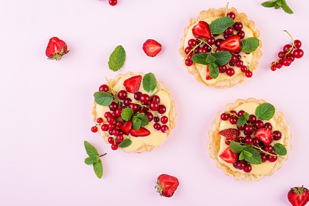 Tortas com morangos, groselha e chantilly, decoradas com folhas de hortelã