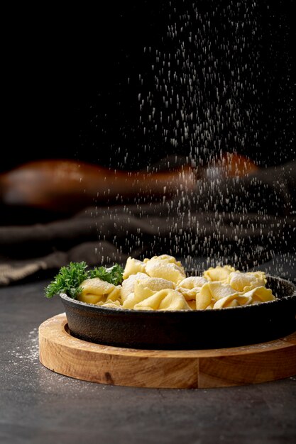 Tortellini em chapa metálica escura em um carrinho de madeira