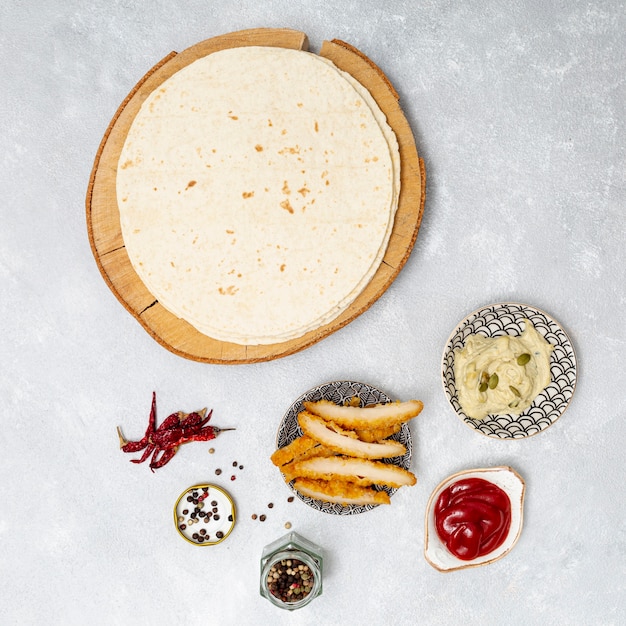 Tortilla redonda com mergulhos picantes ao lado de frango assado