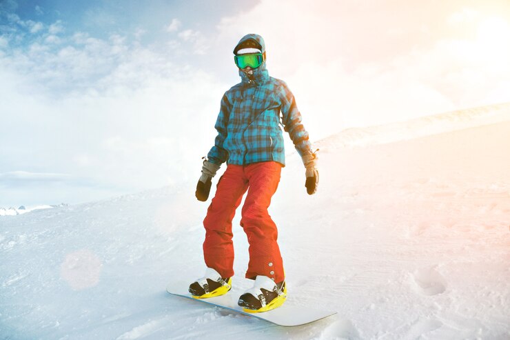 Foto grátis totalmente equipado e coberto de frio, o snowboarder iniciante usa óculos de neve, posando no topo da montanha
