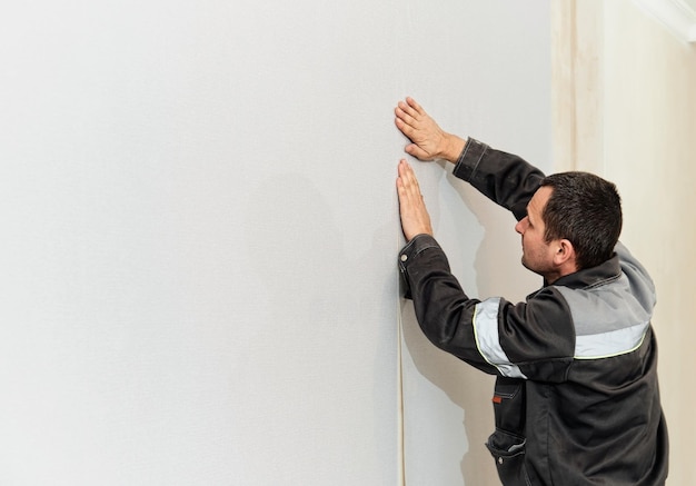 Trabalhador colando papéis de parede colando papéis de parede em casa trabalhador homem está colocando papéis de parede na parede conceito de renovação doméstica