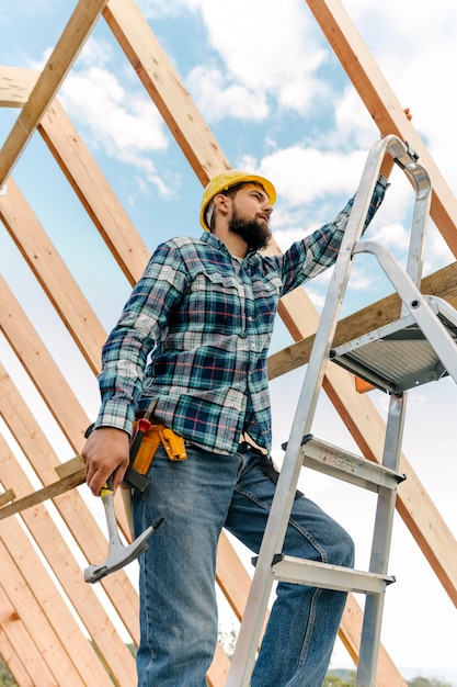 Trabalhador com capacete e martelo construindo uma casa