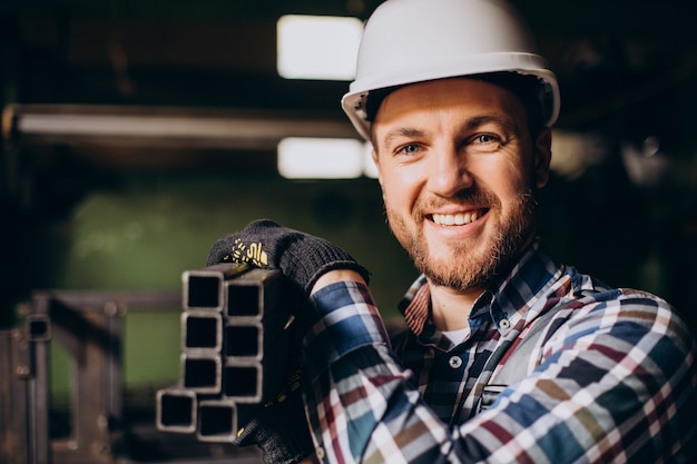 Trabalhador com capacete trabalhando com construções de metal na fábrica