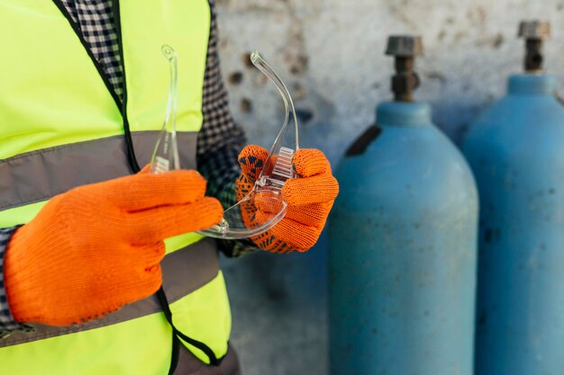 Trabalhador com luvas segurando óculos de proteção