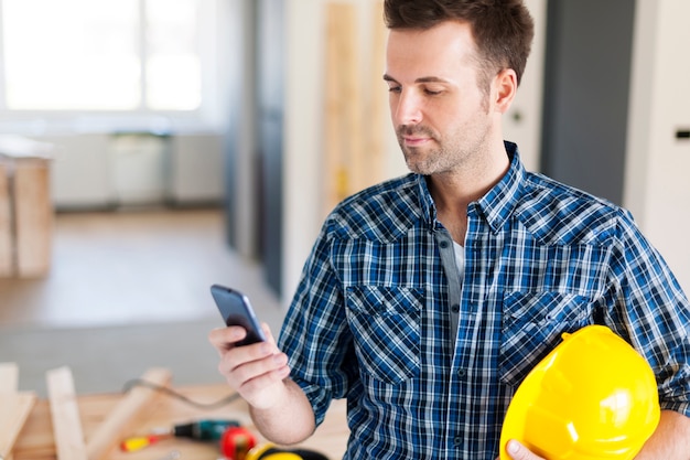 Trabalhador da construção civil com telefone celular contemporâneo