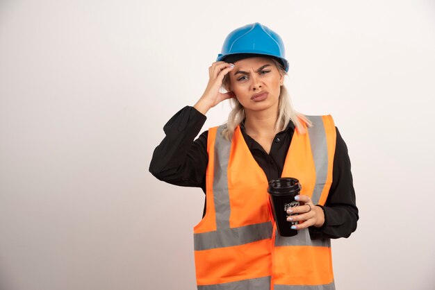 Trabalhador da construção civil com uma xícara de chá, tendo dor de cabeça. Foto de alta qualidade