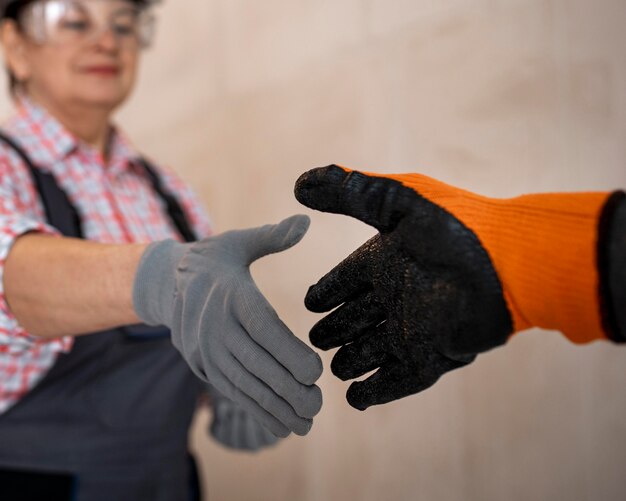 Trabalhador da construção civil feminino com capacete e luvas dando um aperto de mão