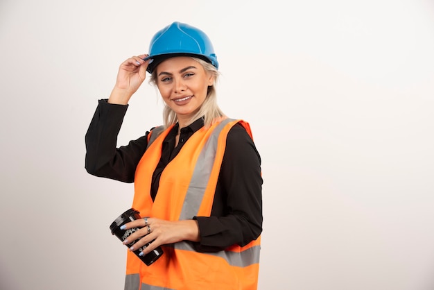 Trabalhador da construção civil posando com uma xícara de chá no fundo branco. Foto de alta qualidade