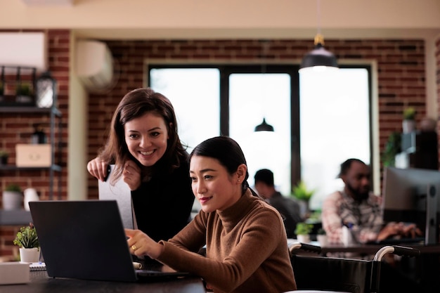 Trabalhador da empresa trabalhando com cadeirante no escritório, fazendo trabalho em equipe para planejar a estratégia. Mulher com deficiência crônica e condição de saúde analisando o relatório do projeto, conversando com o colega.