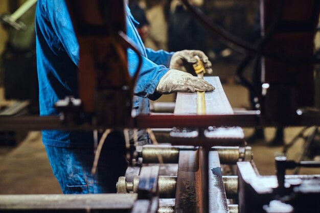 Trabalhador da fábrica de metal está tomando medidas do pedaço de trilho.