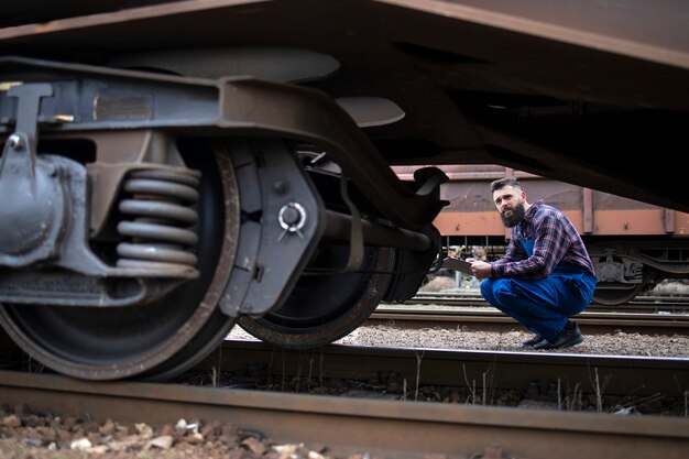 Trabalhador da ferrovia inspecionando rodas e freios do trem de carga