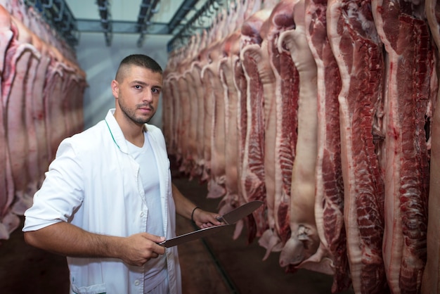 Foto grátis trabalhador da indústria alimentícia manuseando carne crua fresca em matadouro e preparando a carne para o mercado