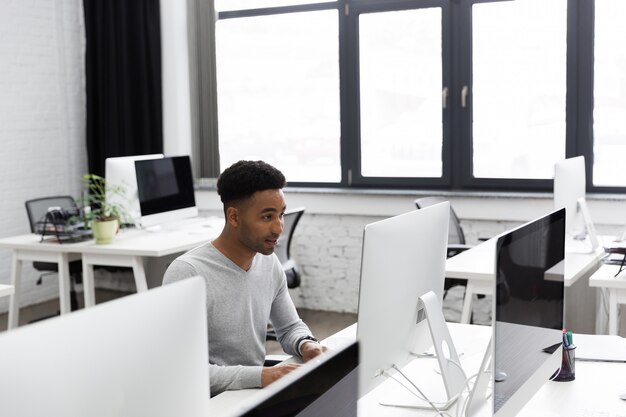 Trabalhador de escritório africano jovem sentado em uma mesa