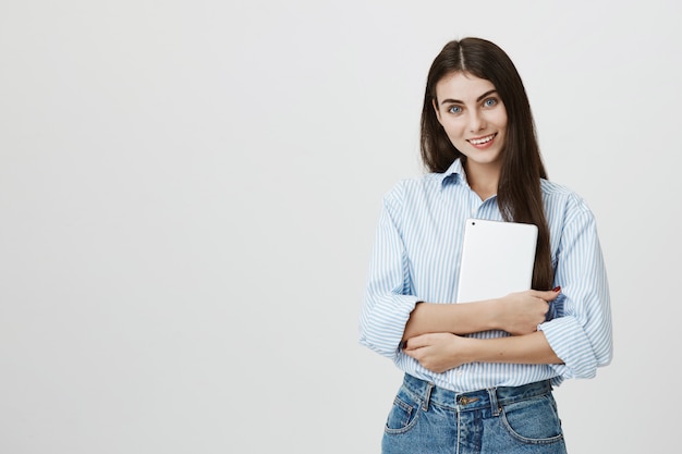 Trabalhador de escritório atraente segurando um tablet digital e sorrindo