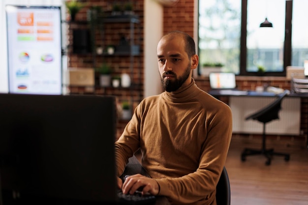 Foto grátis trabalhador de escritório de agência de desenvolvimento analisando vendas de projetos e startup de fintech. empresário sentado à mesa no escritório da empresa de marketing desenvolvendo estratégia financeira e gestão contábil.