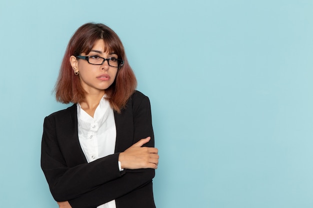 Trabalhador de escritório feminino em terno estrito posando na superfície azul