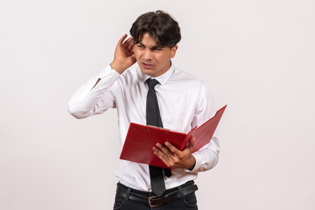 Trabalhador de escritório masculino de frente segurando uma pasta vermelha em uma mesa branca, trabalho, escritório, trabalho humano