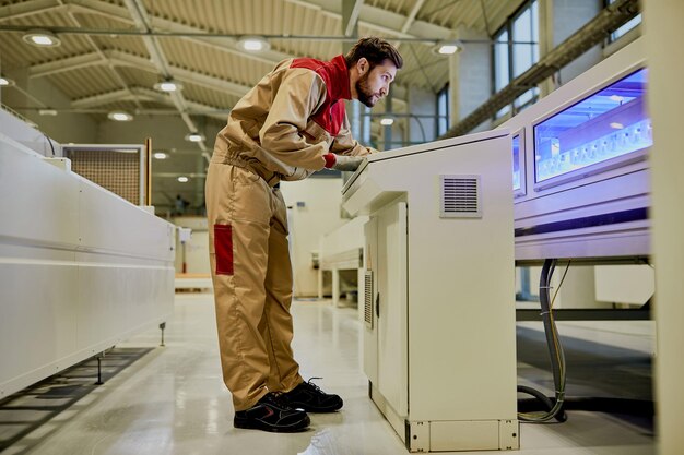 Trabalhador de linha de produção operando máquina automatizada em instalações industriais de carpintaria