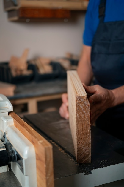 Trabalhador de madeira em sua loja trabalhando com ferramentas e equipamentos