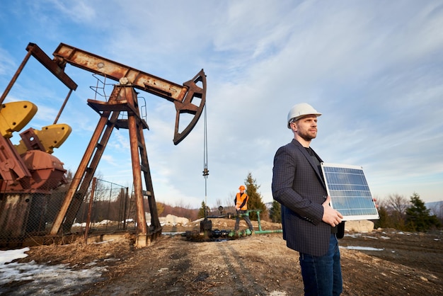 Trabalhador de petróleo no capacete segurando o painel solar