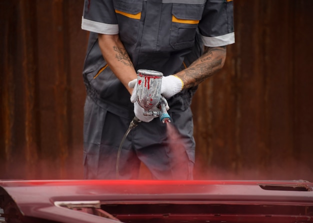 Trabalhador de vista frontal pulverizando tinta em pó de goma