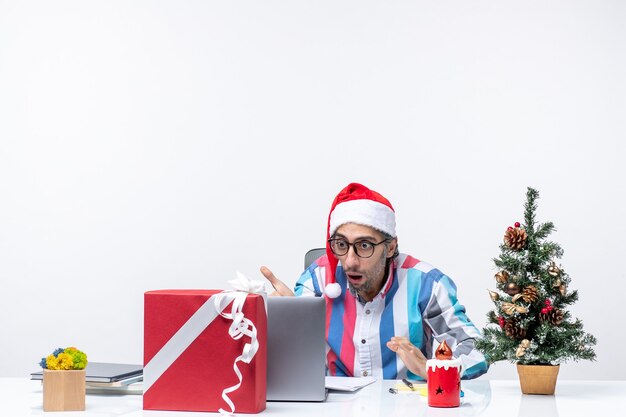 Trabalhador do sexo masculino de vista frontal sentado em seu lugar escrevendo notas e usando o laptop