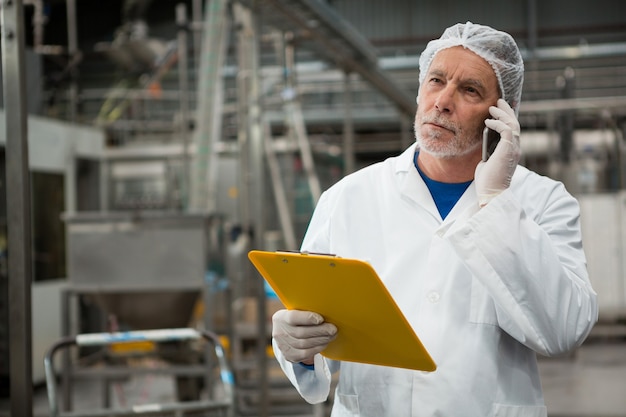 Foto grátis trabalhador do sexo masculino falando no celular em uma fábrica de bebidas geladas