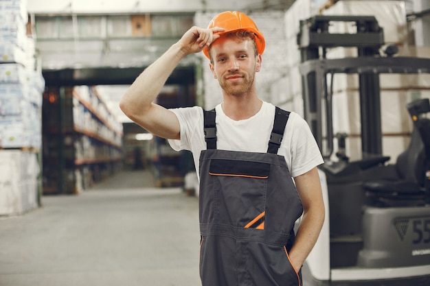 Trabalhador industrial dentro de casa na fábrica. Jovem técnico com capacete laranja.