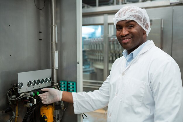 Trabalhador masculino confiante operando máquina em fábrica de suco