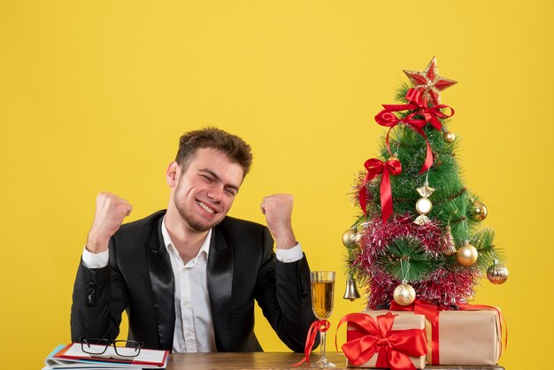 Trabalhador masculino sentado atrás de seu local de trabalho regozijando-se no amarelo