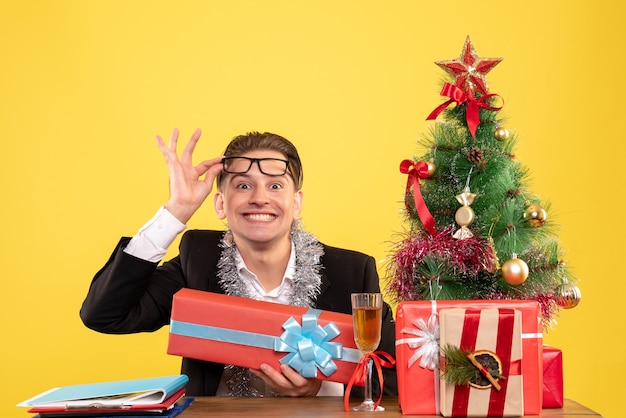 Trabalhador masculino sentado de frente com presentes de natal