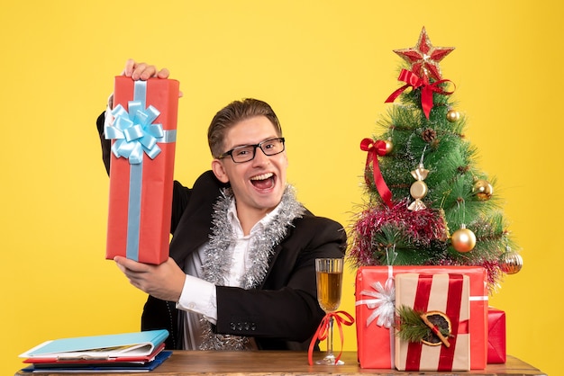 Trabalhador masculino sentado de frente e segurando um presente de natal