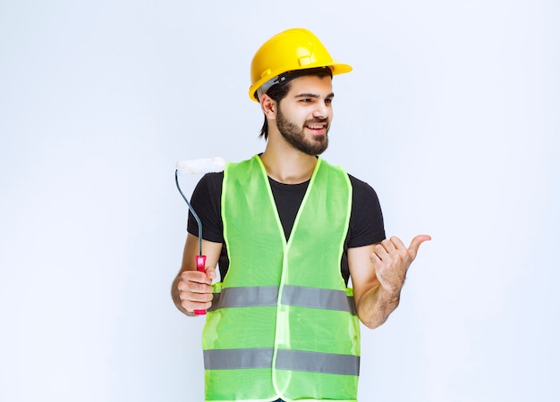 Trabalhador segurando um rolo aparador branco para pintura de parede.