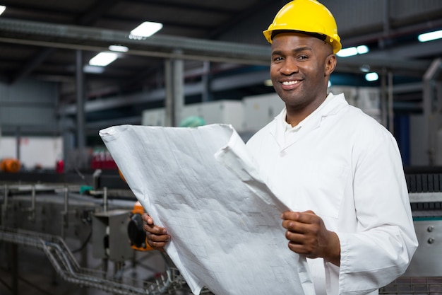 Trabalhador sorridente lendo instruções na fábrica de suco
