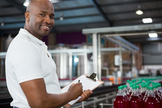 Trabalhador sorridente observando produtos na fábrica de suco