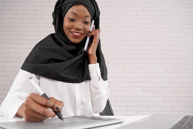 Trabalhadora de escritório feminina falando no telefone escrevendo sorrindo